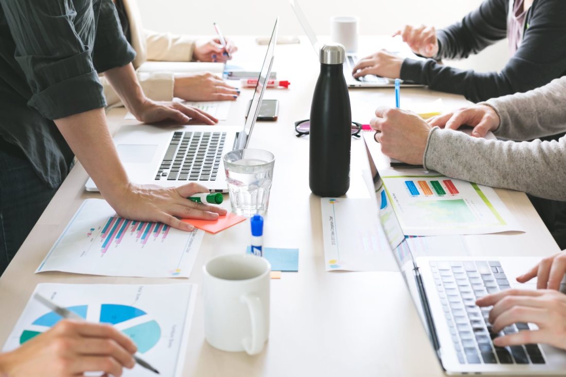 Menschen arbeiten zusammen an Laptops am Tisch