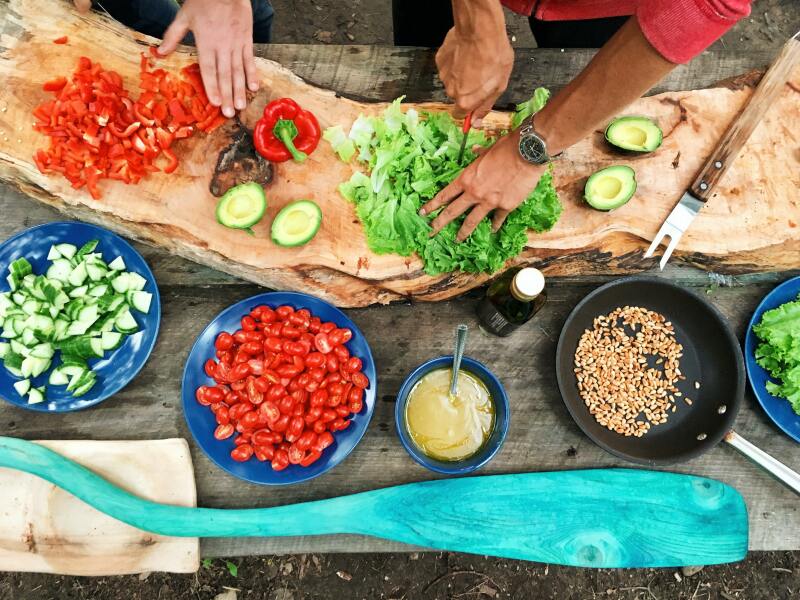 Salat wird auf einem Holzbrett geschnitten